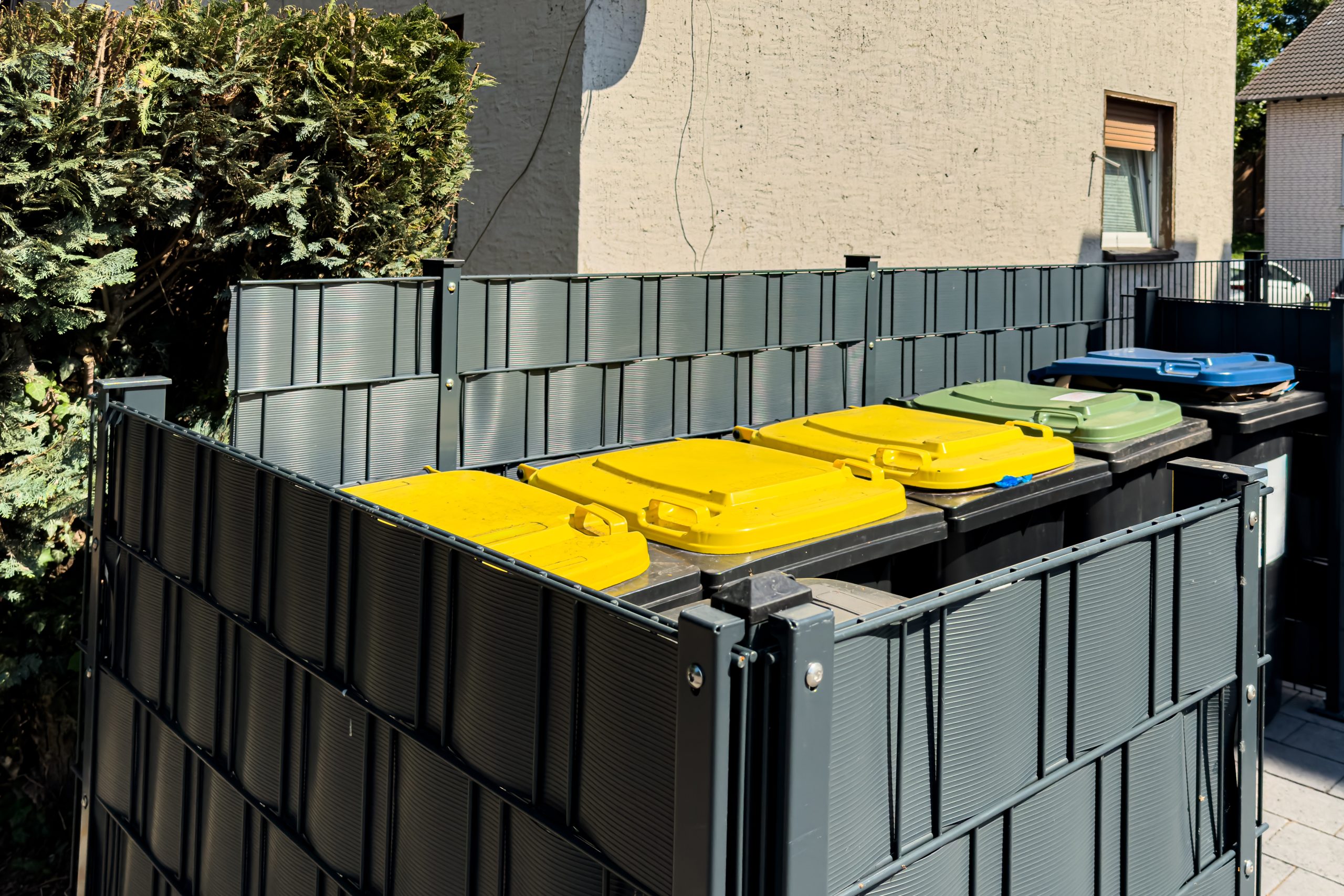 recycling bins organized behind a residential building photo